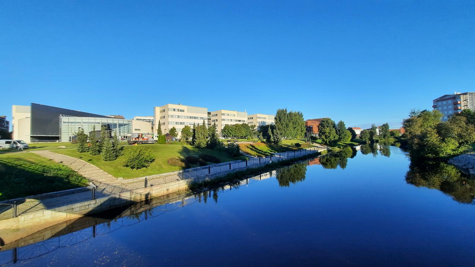 Die modernen, eckigen Geb?ude der Sein?joki University of Applied Sciences sind unter einem wolkenlosen blauen Himmel an einem Flussufer zu sehen.